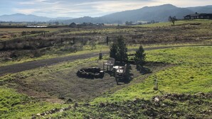 A rural landscape with a fenced area, a wooden bench, and a small structure. - Immaculate and private 2-bedroom house, close to everything, pet friendly (Central Point)