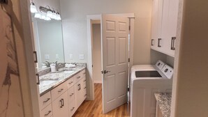 A compact laundry room with a washing machine, a dryer, and a sink with a mirror above it. - Immaculate and private 2-bedroom house, close to everything, pet friendly (Central Point)