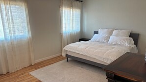 A bedroom with a bed, a nightstand, a wooden floor, and a carpet. - Immaculate and private 2-bedroom house, close to everything, pet friendly (Central Point)