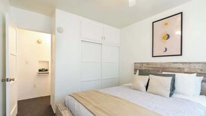 Un dormitorio con cama, armario, mesita de noche y un cuadro en la pared.