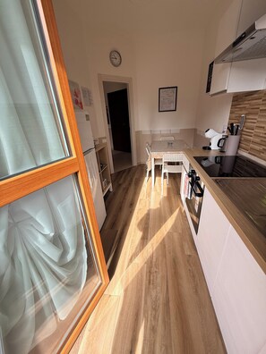 A kitchen with a dining table, chairs, a clock, and a coffee machine.