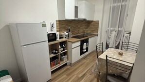 Una cocina compacta equipada con refrigerador, microondas, pileta y un comedor con mesa y sillas.