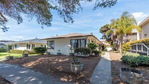 A residential house with a front yard, a pathway, and a small garden area with potted plants. - Cute Pacific Beach Unit! Walk to the Beach! (San Diego)