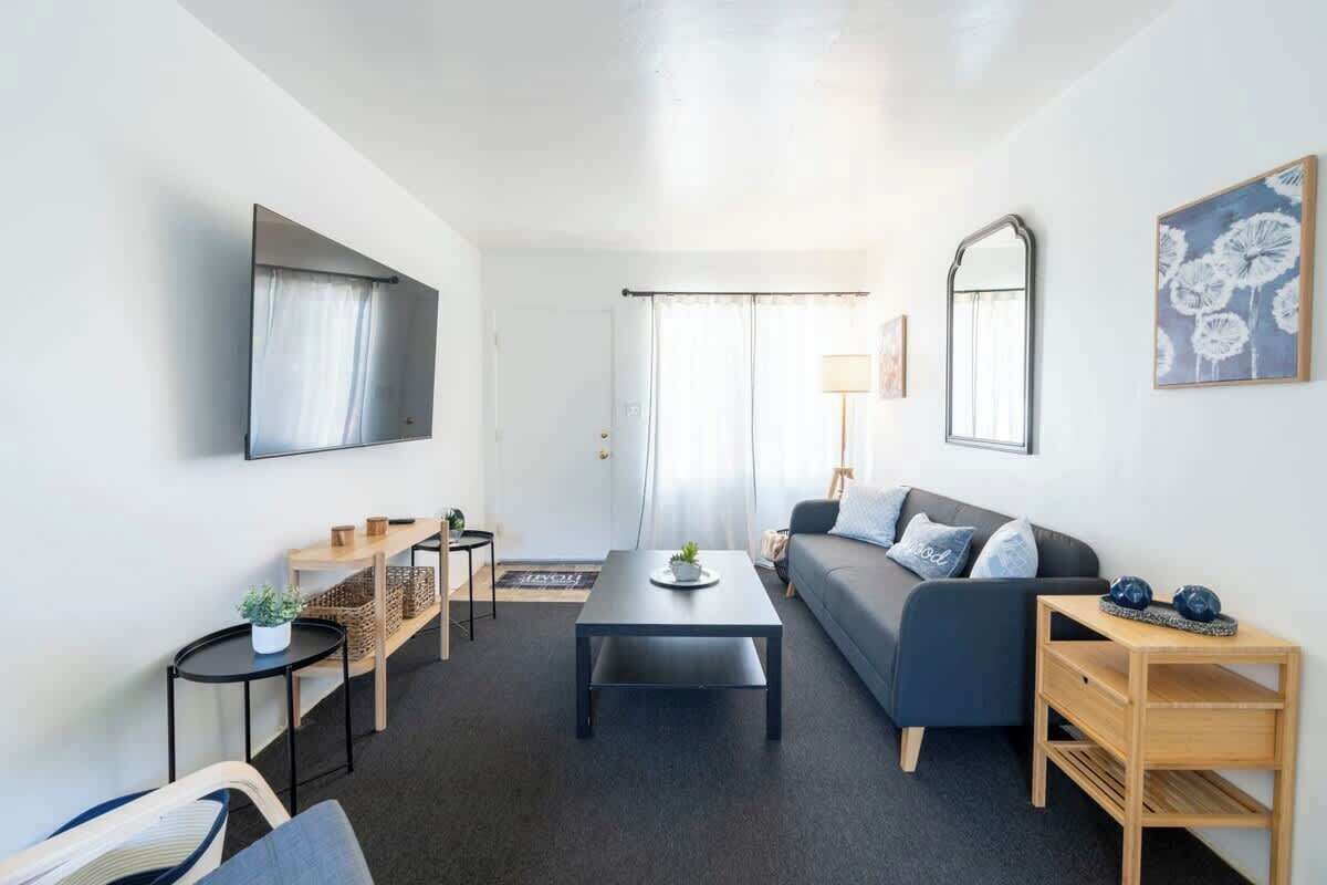 A modern living room with a sofa, coffee table, and a TV mounted on the wall.