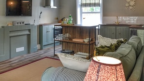 A modern kitchen with a built-in oven, a dining area with a sofa, and a large window providing natural light.