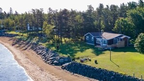A coastal property with a house, a beach, and a forested area.