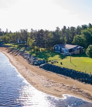 A coastal property with a house, a beach, and a forested area.