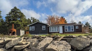 A house with a chimney, a front porch, and a large rock formation in the foreground.