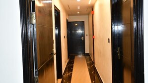 A hallway with black doors, a marble floor, and a ceiling with recessed lighting. - Hotel MKG Inn Club and Bar Jaipur (Jaipur)
