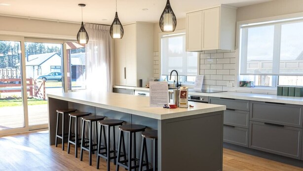 A modern kitchen with a central island, bar stools, and pendant lighting.