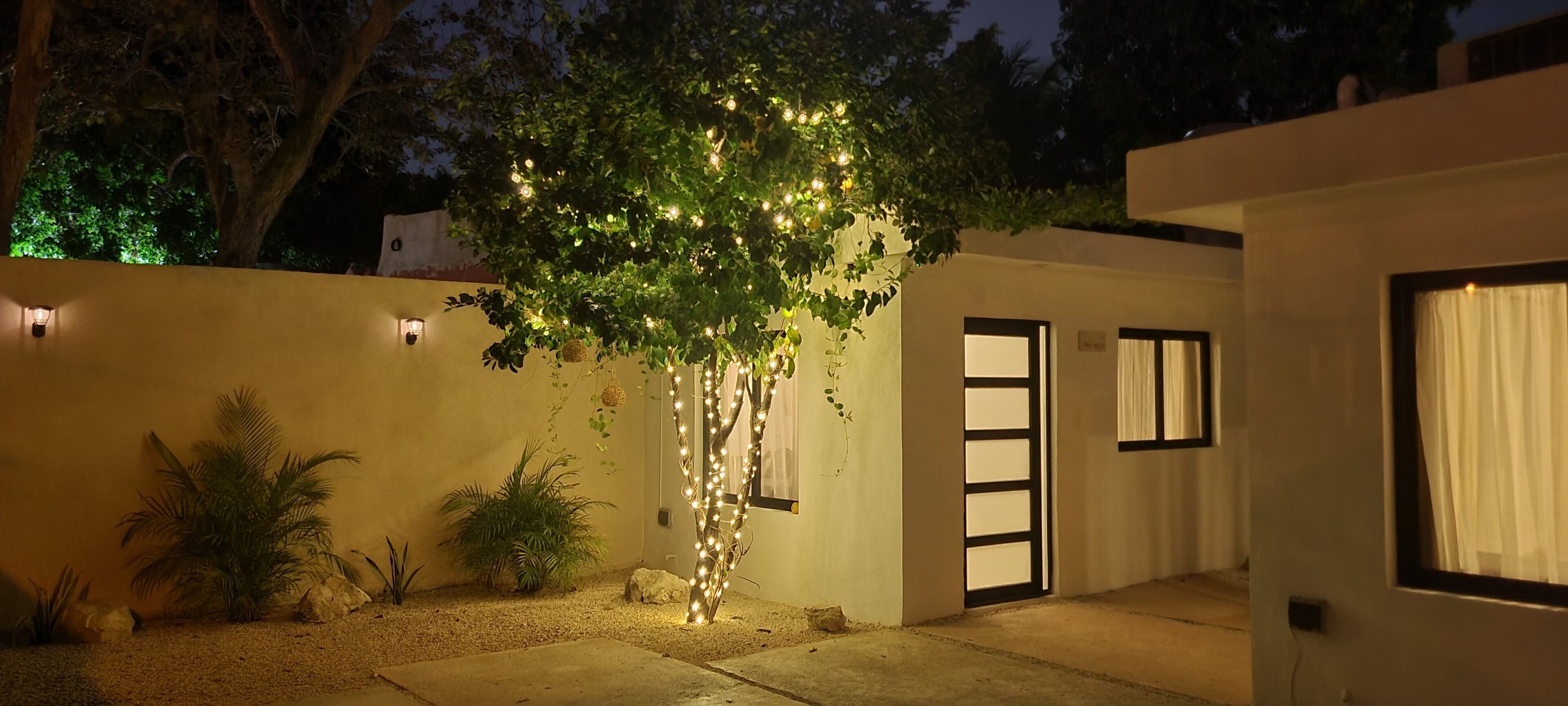 Una casa moderna con un árbol decorado con luces, una puerta y una ventana.