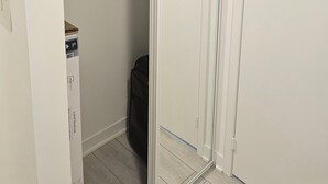 Ein begehbarer Kleiderschrank mit weißer Tür, einer Kleiderstange und einem kleinen Gerät.