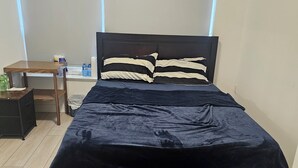 Ein Schlafzimmer mit Bett, Nachttisch und Fenster.