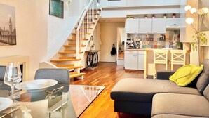 Een modern appartement met een eethoek, woonkamer, keuken en een trap naar een hoger gelegen verdieping.