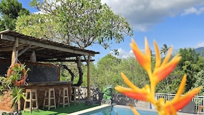 A swimming pool with a wooden deck, a barbecue area, and a covered seating area. - Eco Moringa Garden (Bali)