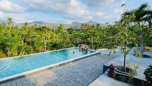 A swimming pool with a view of lush greenery and mountains in the background. - Eco Moringa Garden (Bali)