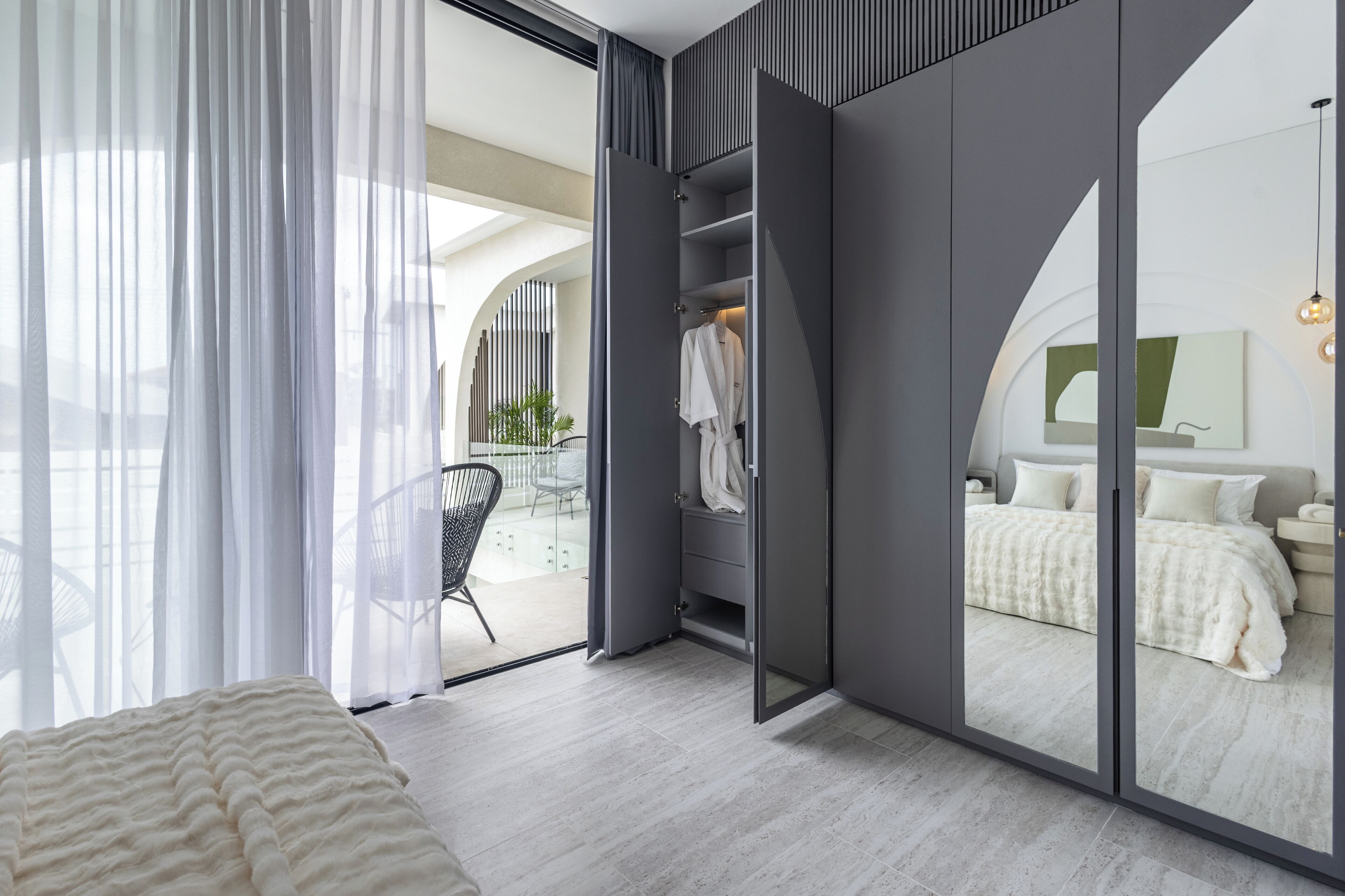 Et moderne soveværelse med en stor seng, et walk-in closet og udsigt til balkonen.