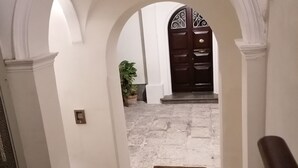 A hallway with an arched doorway leading to a room with a dark wooden door. - BelliniStay - Apartment in the heart of the city, between station, port and beaches. (Trapani)