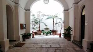 A corridor with arched ceilings, stone flooring, and potted plants. - BelliniStay - Apartment in the heart of the city, between station, port and beaches. (Trapani)