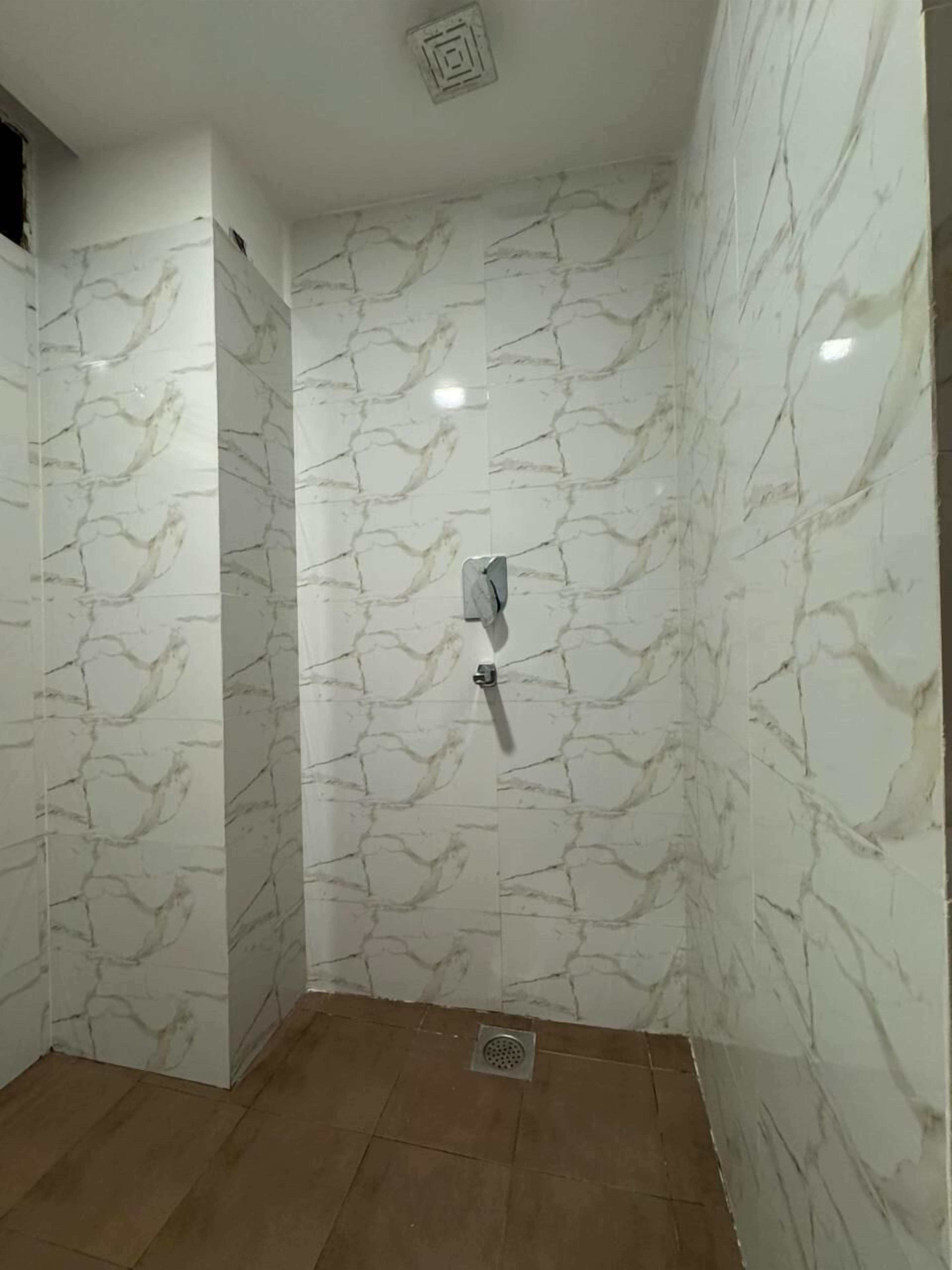 A bathroom with white marble walls and a shower area.
