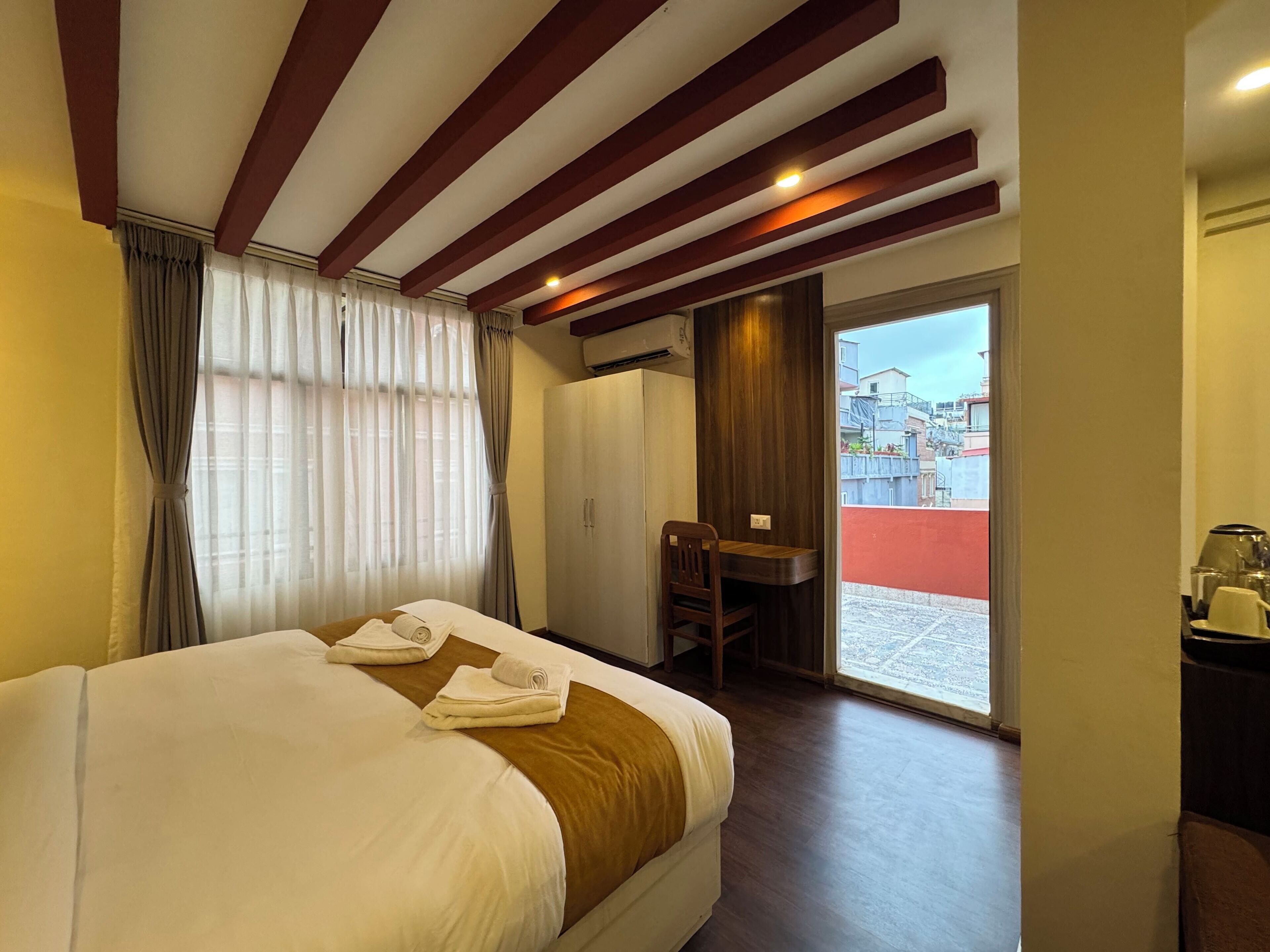 A hotel room with a large bed, a desk, and a view of the outside.
