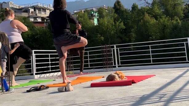 A group of people practicing yoga on an outdoor platform with a view of mountains in the background. - Tranquil Trails Naddi SunRise  (Dharamshala)