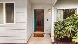 Une maison avec un porche à l’avant, une porte donnant sur l’intérieur et un petit luminaire extérieur.