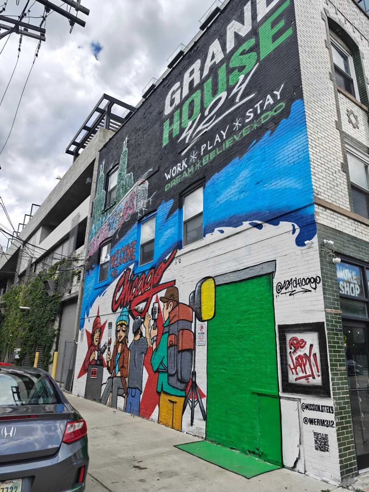 A building with a mural, a green door, and a sign that says 'Grand House.'