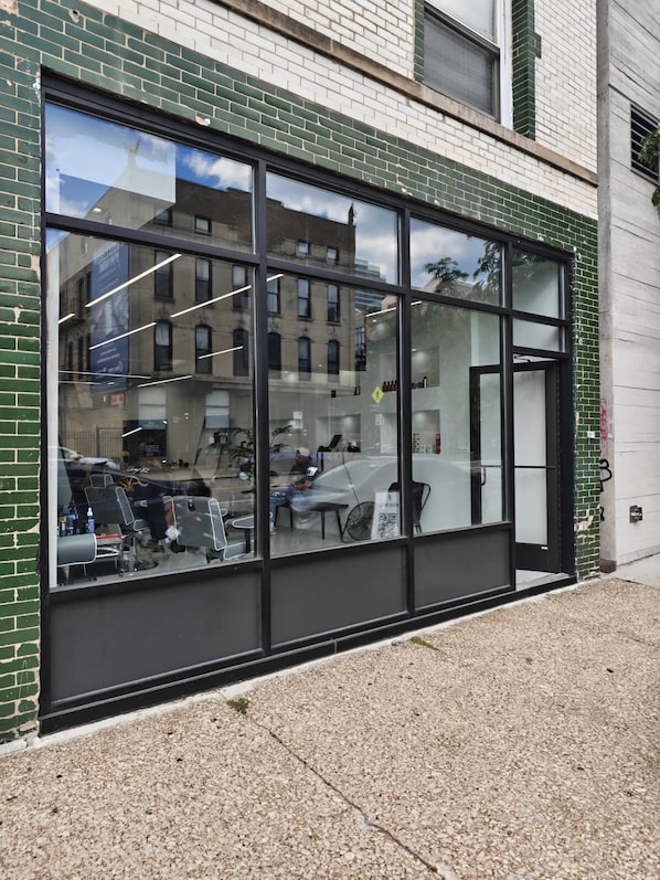 A building with large windows, a brick facade, and a visible reflection of a bicycle and a person. - Grand House (Chicago)