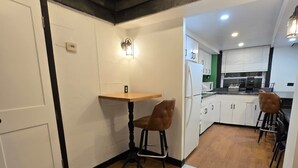 A modern kitchen with white cabinets, a wooden dining table, and two brown chairs. - Grand House (Chicago)