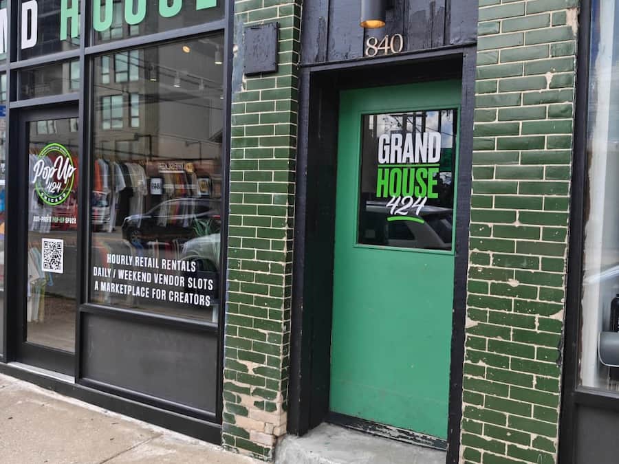 Une devanture de magasin avec une porte verte portant l’inscription « Grand House 424 » et une enseigne au-dessus de la porte.