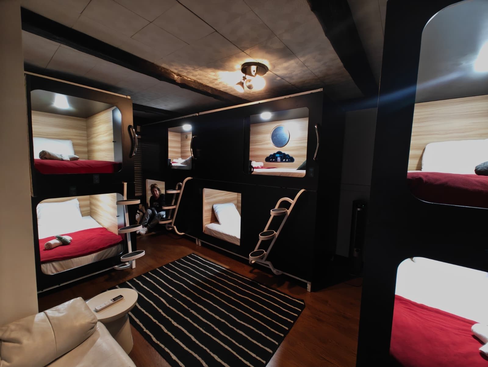 A compact, modern room with bunk beds, a small seating area, and a television.