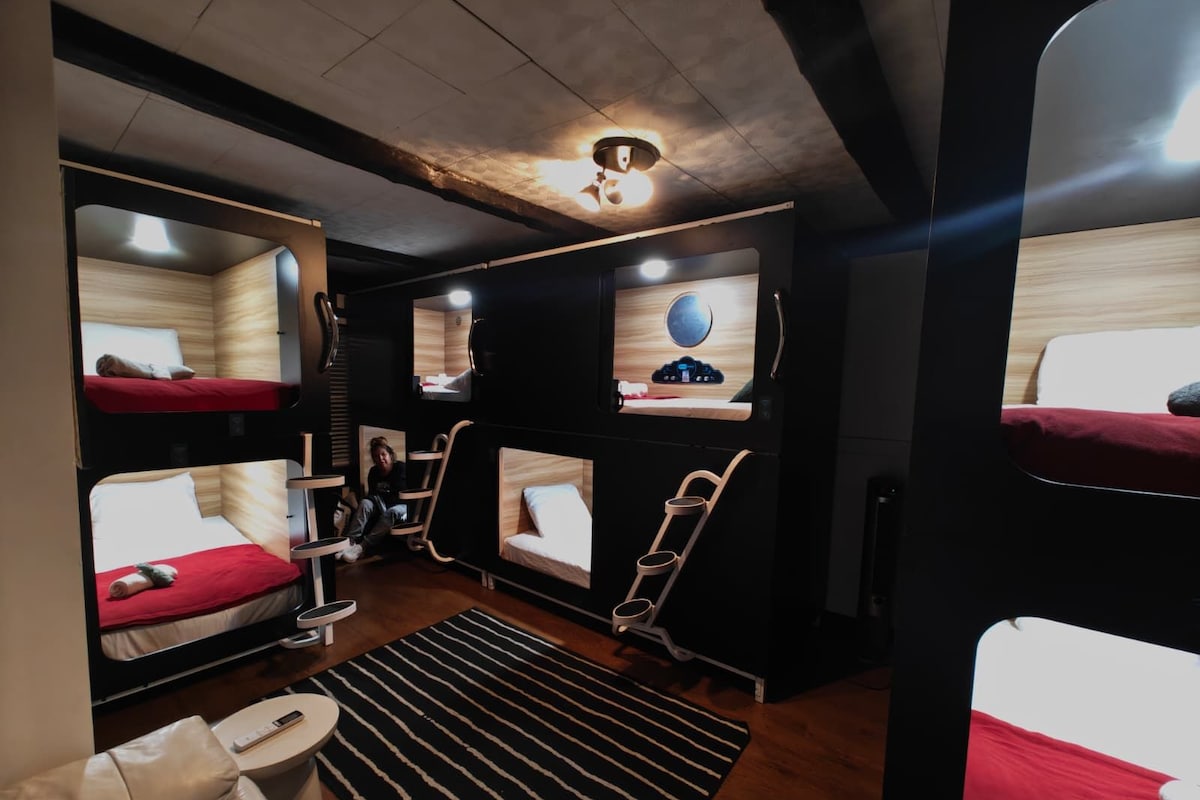 A compact, modern room with bunk beds, a small seating area, and a television.