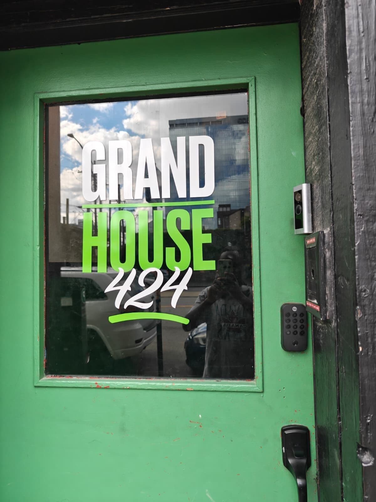 En grön dörr med ett fönster där det står ”GRAND HOUSE 427” och ett lås med knappsats.