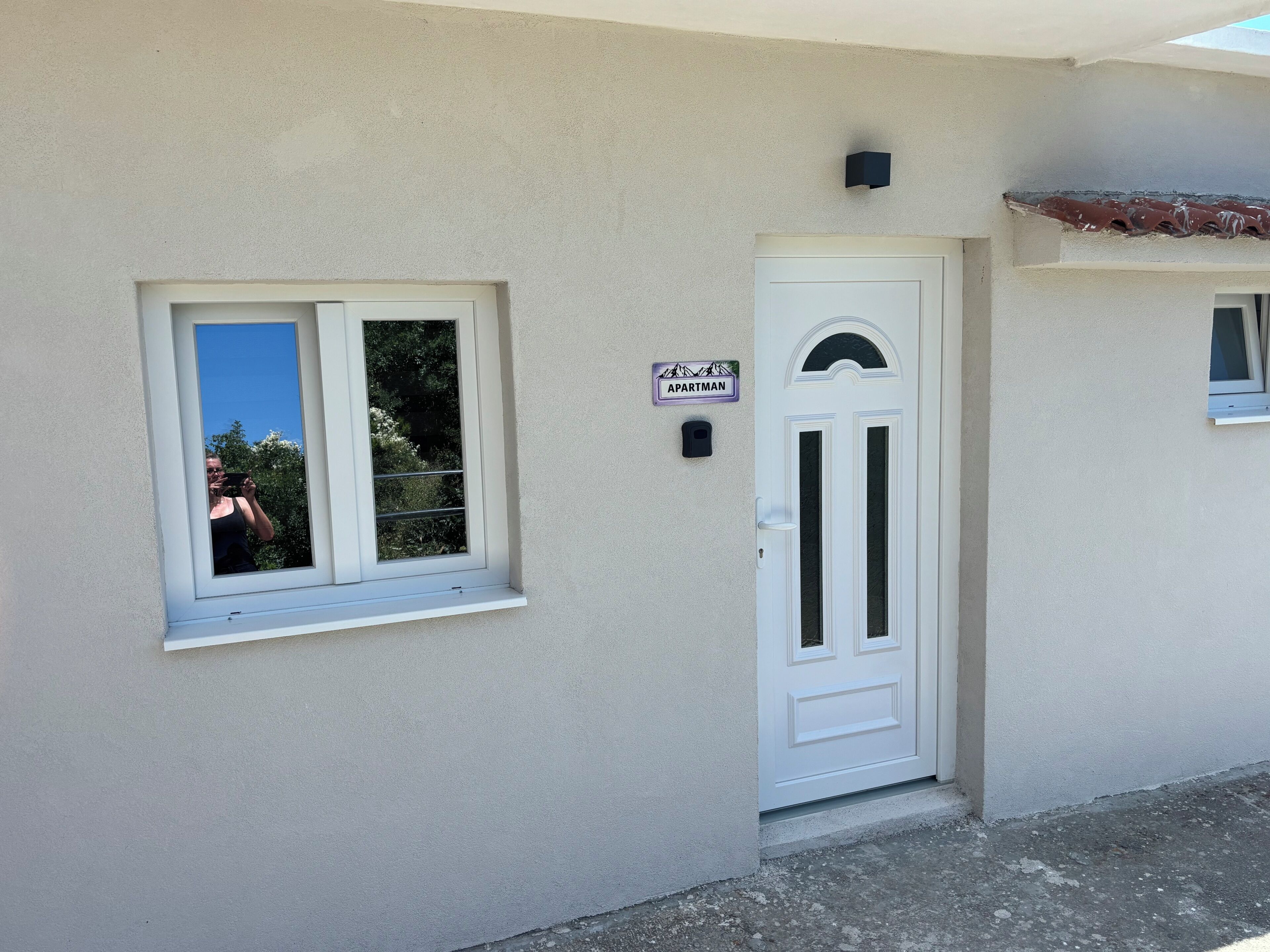 Un edificio con una puerta blanca, una ventana y un letrero que dice 'APARTMAN'.