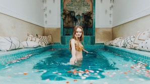 A woman in a pool with decorative pillows and a tiled wall with a floral pattern. - Kenzara Suites & Pool, Your private escape (Marrakesh)
