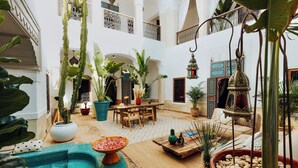 A spacious courtyard with a pool, potted plants, a wooden table, and a hanging lantern. - Kenzara Suites & Pool, Your private escape (Marrakesh)