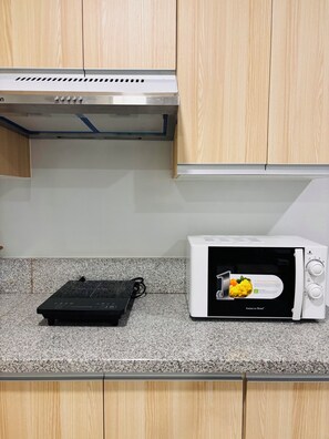 Una cocina con microondas, tostadora y campana extractora.