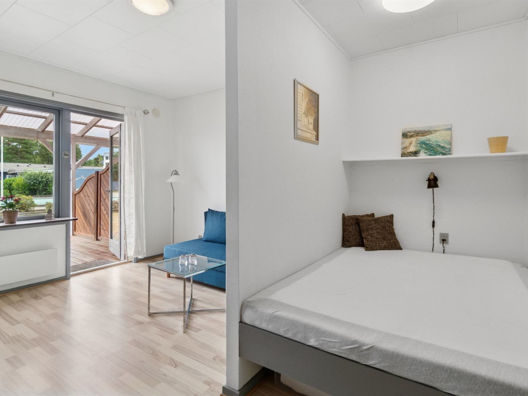 A modern bedroom with a large bed, a glass table, and a blue sofa.