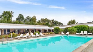 A swimming pool with white lounge chairs and a covered seating area.