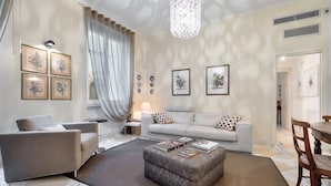 Una sala de estar moderna con un sofá, un sillón, un reposapiés y una mesa de comedor con sillas.