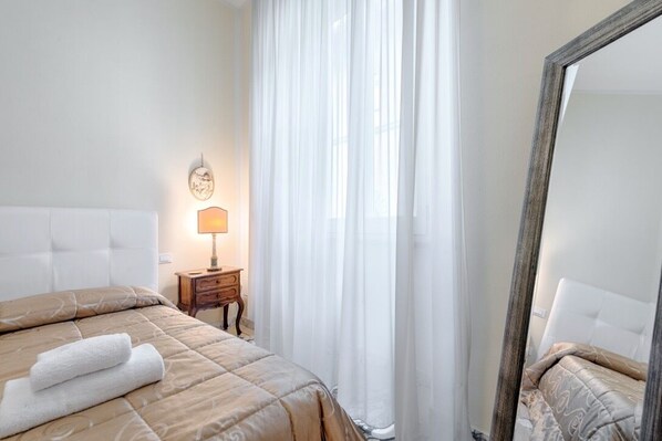 A hotel room with a bed, a bedside table with a lamp, and a large mirror. - Apartment in ancient palace near the cathedral in the heart of the Old Town (Firenze)