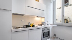 Una cocina moderna con armarios blancos, un lavamanos de acero inoxidable y un horno.