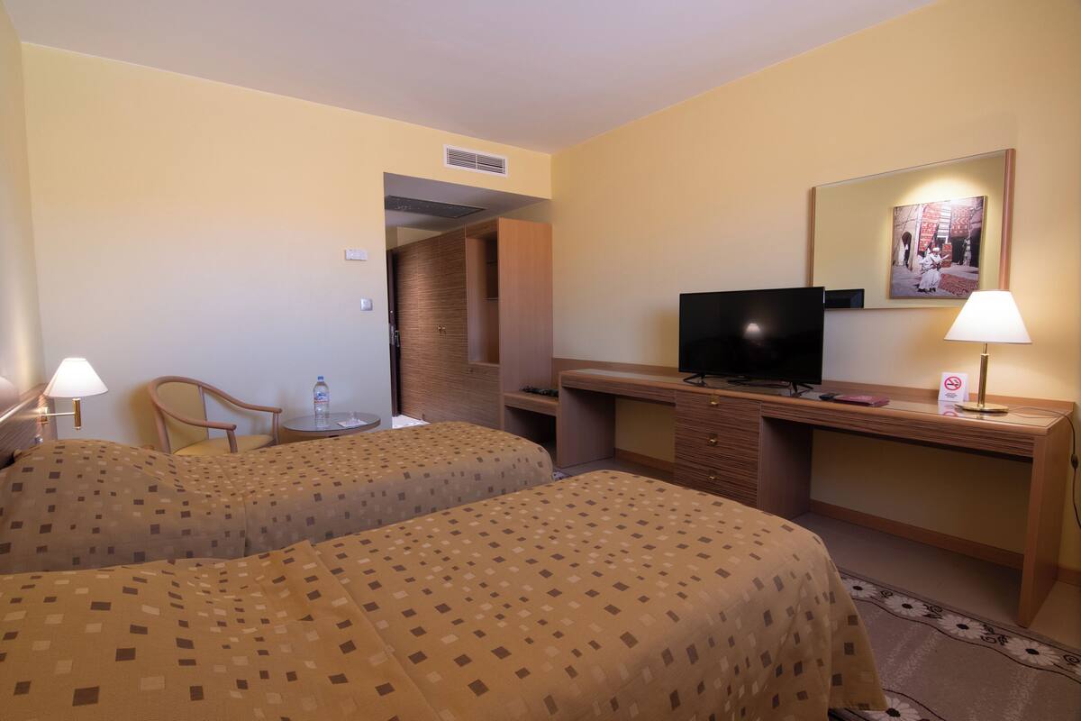 Een hotelkamer met twee bedden, een bureau, een televisie en een stoel.