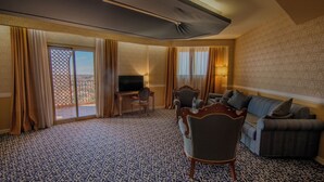 Een hotelkamer met een groot raam, een televisie, een bank, een stoel en een bureau.