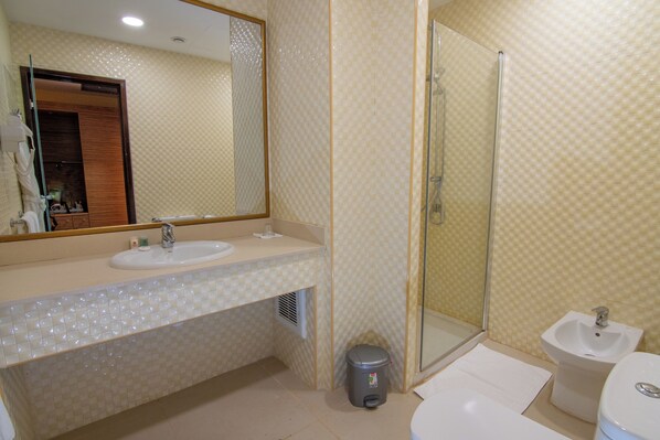 Un baño con lavamanos, espejo, ducha e inodoro con ducha.