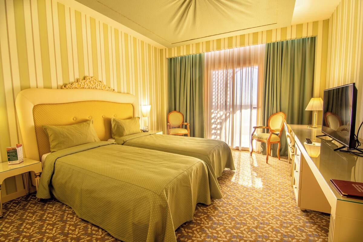 Een hotelkamer met twee bedden, een bureau met een televisie en een stoel.