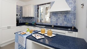 A modern kitchen with white cabinets, a blue and white patterned backsplash, and a dark blue countertop. - Villa Dei in Positano - Double Room (Positano)