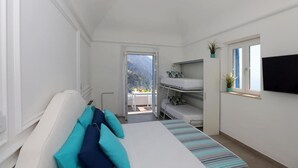 A bedroom with a bed, a TV mounted on the wall, a bunk bed, and a balcony with a mountain view. - Villa Dei in Positano - Double Room (Positano)