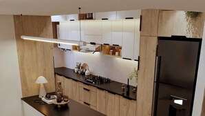 A modern kitchen with wooden cabinets, a black countertop, and a built-in refrigerator.